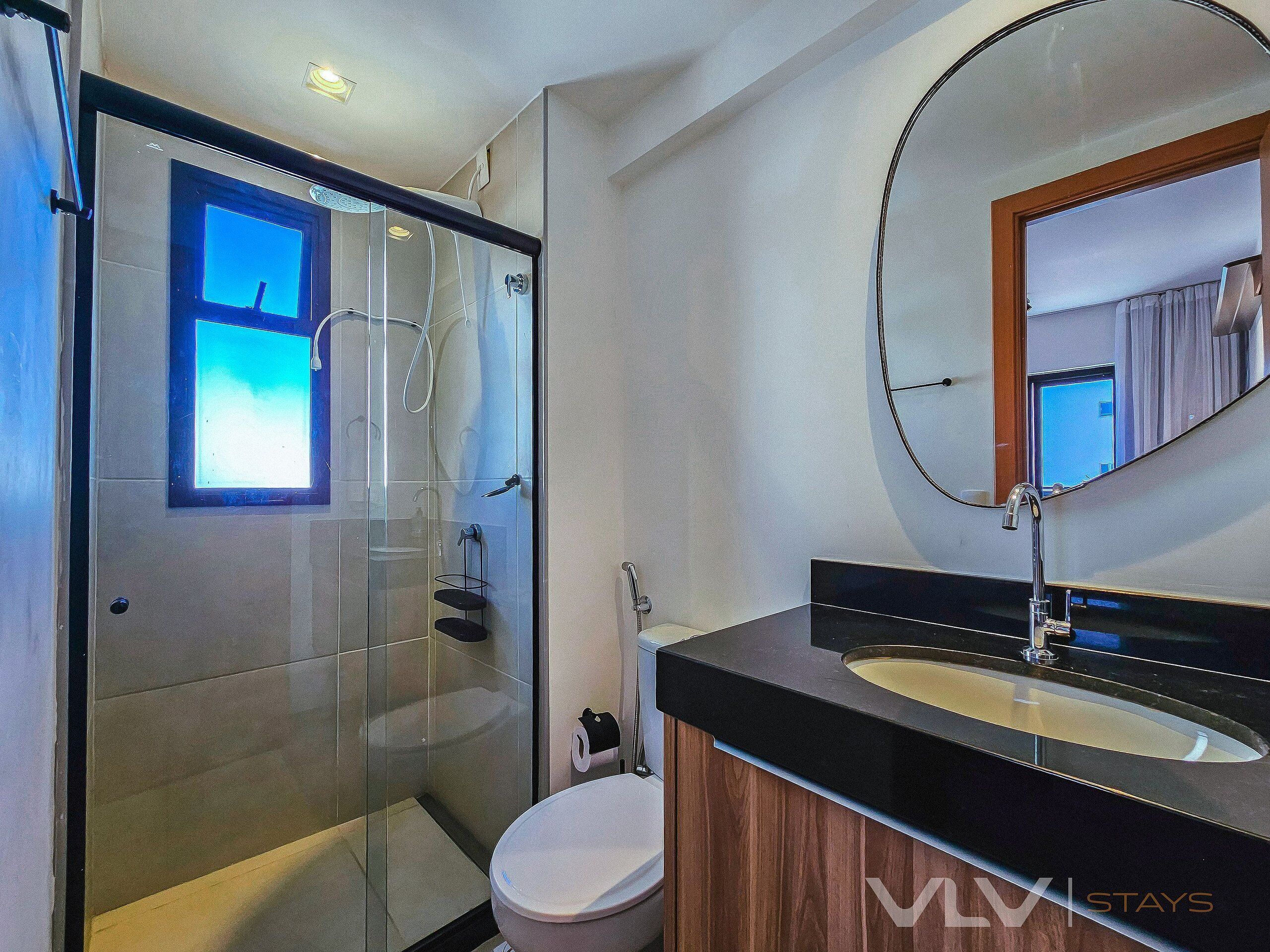 Un baño moderno con ducha de vidrio, tocador de madera y un espejo grande.