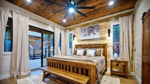 A bedroom with a wooden bed, a bench, a small table, and a ceiling fan. - Rare Breed | 8 Bedrooms | Pool | Pickleball | Playset | ATV access (Broken Bow)