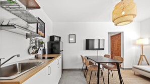 Una cocina moderna con lavavajillas integrado, encimera de madera y comedor con sillas de mimbre y una mesa oscura.
