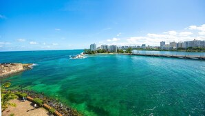 A coastal cityscape with a clear blue sky, a bridge connecting two land masses, and a calm sea. - Oceanfront Terrace Condado Near The Beach (San Juan)