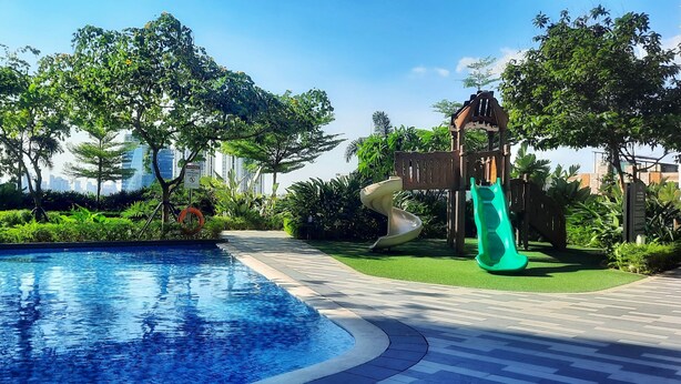 A swimming pool surrounded by lush greenery and a slide.