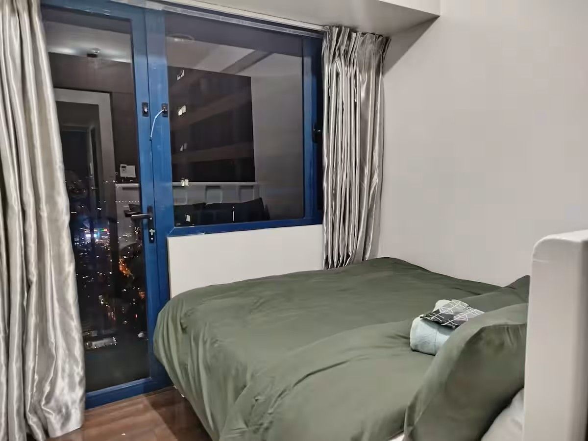 Una camera da letto con un letto, una finestra con tende e vista sulla città illuminata di notte.