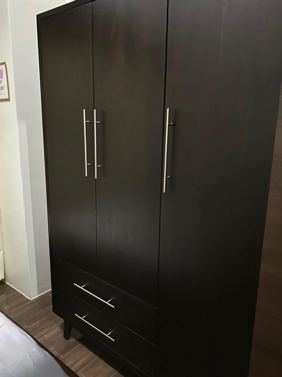 A large, dark-colored wardrobe with two doors and a lower shelf.