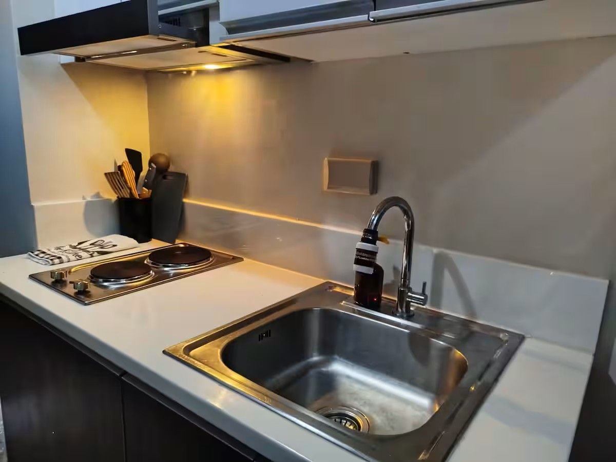 A kitchen with a stainless steel sink, a stove, and a range hood.