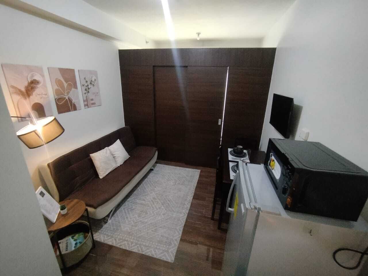 Ein gemütlicher, kleiner Wohnbereich mit einer Couch, einem Teppich, einem Fernseher und einer Mikrowelle.