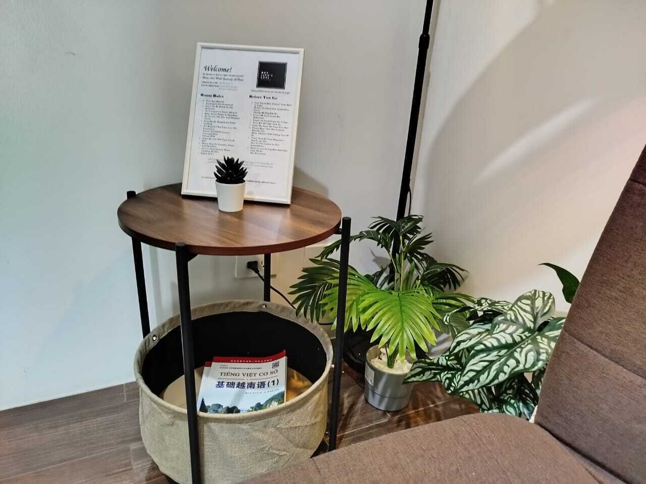Un coin de pièce avec une petite table en bois, une plante en pot et un tableau d’affichage.