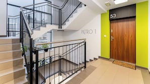 A modern interior with a staircase, a wooden door labeled "53", and a sign "PIETRO 1". - Apartments Deluxe Barcelona 55 (Kraków)