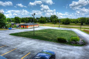 A parking lot with a building, a grassy area, and a road in the background. - Volunteer Inn at Church Hill near Kingsport (Church Hill)