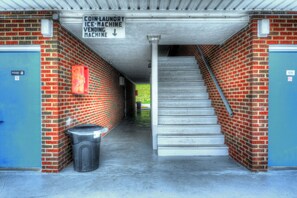 A coin laundry ice machine vending machine sign above a staircase in a building with brick walls and blue doors. - Volunteer Inn at Church Hill near Kingsport (Church Hill)