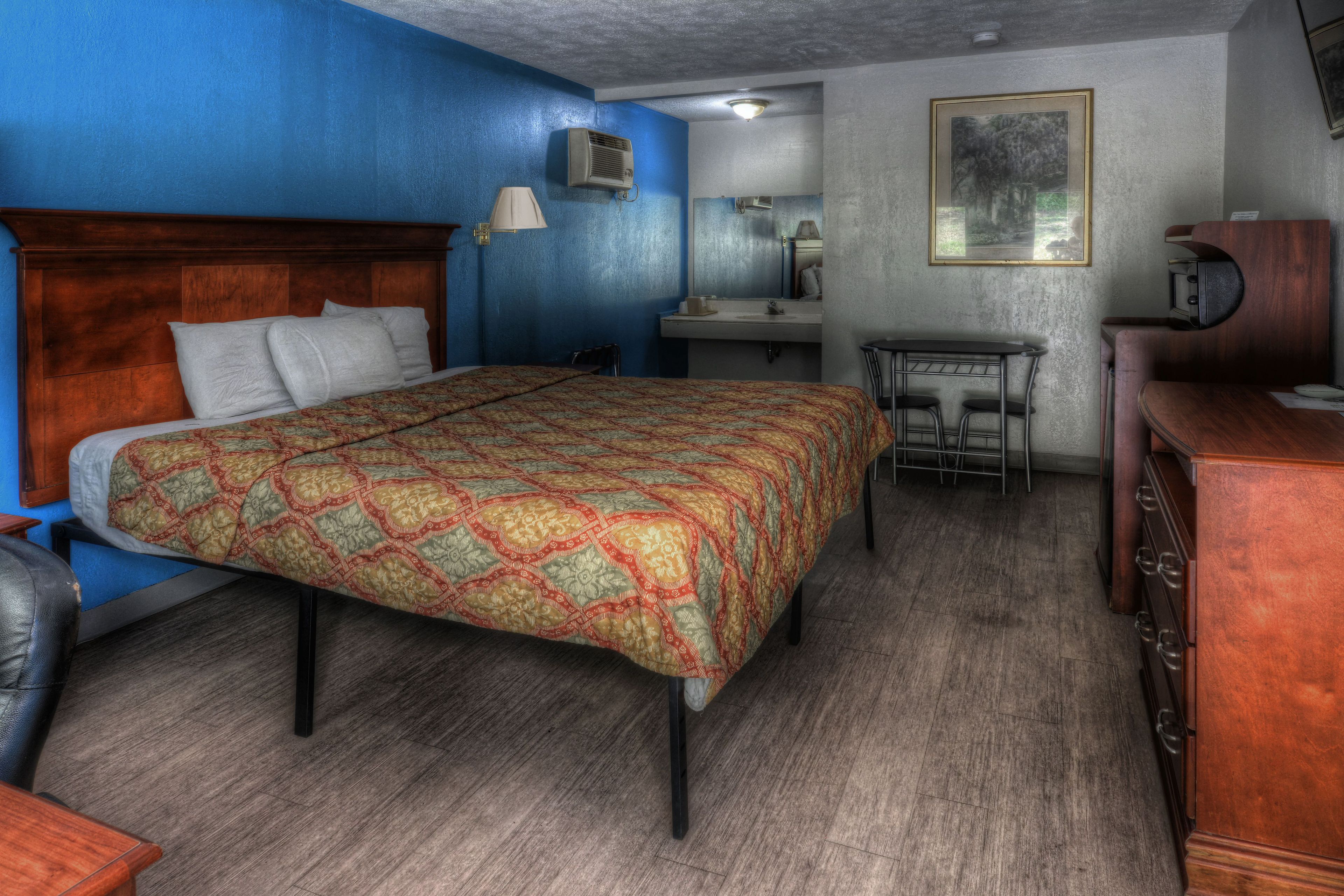 A room with a bed, a desk, a chair, and a dresser.