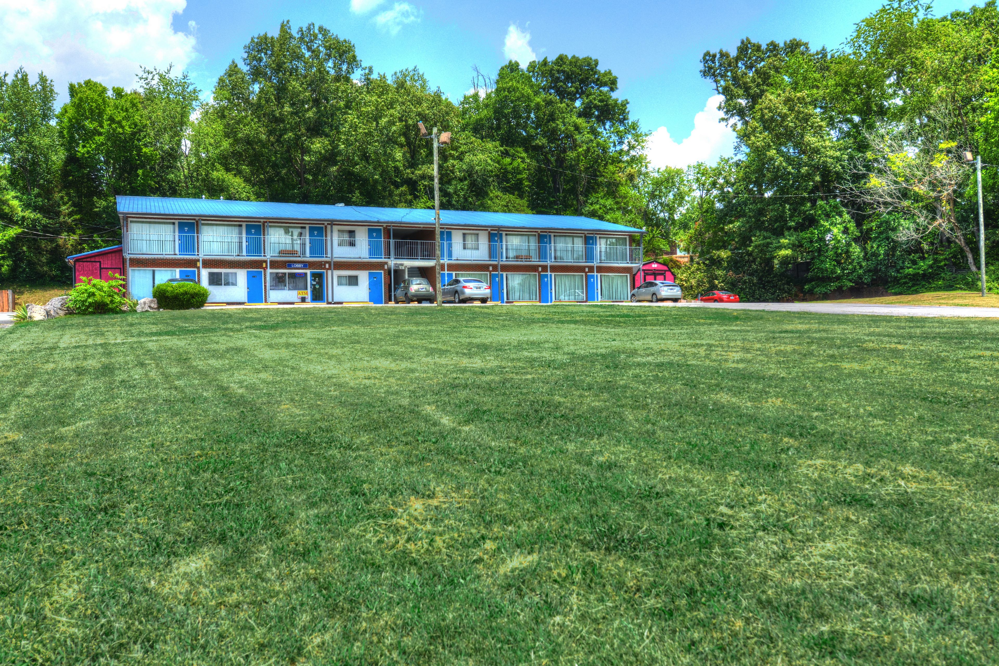 A motel with a blue exterior, multiple rooms, and a parking area.