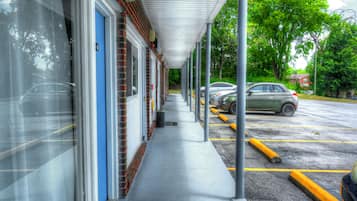A parking area with a covered walkway leading to a building with multiple doors.