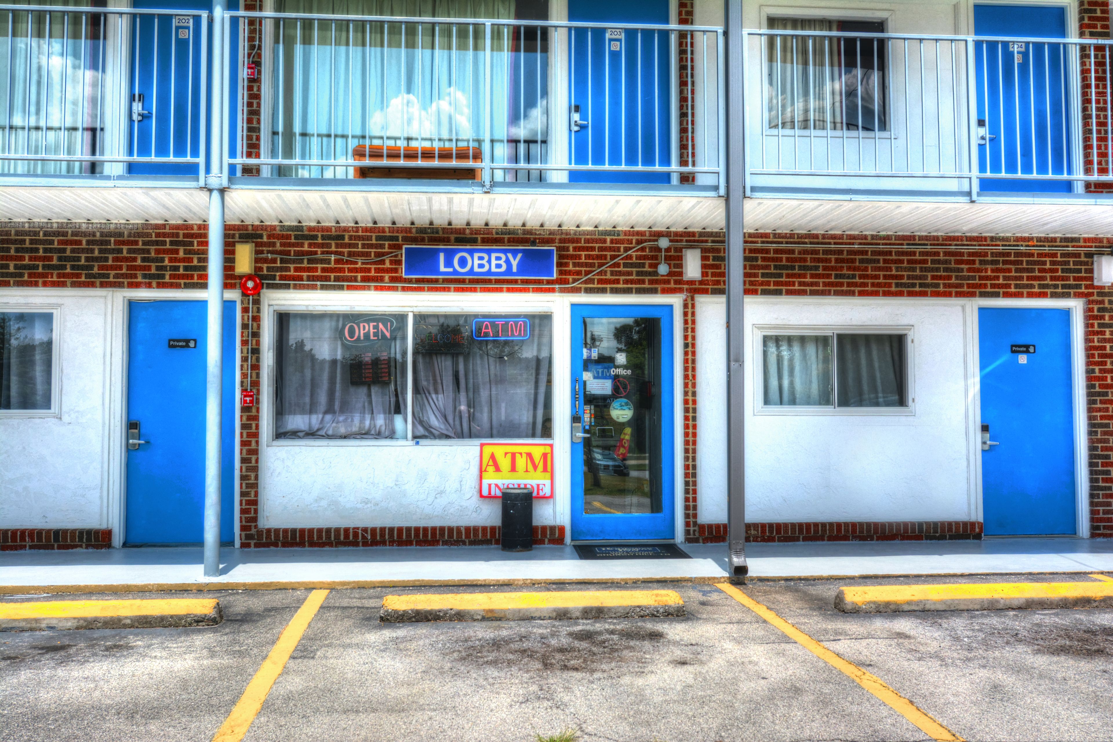 Un edificio con un letrero azul que dice 'Lobby', dos puertas azules y un cajero automático visible.