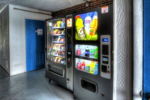 A vending machine with various beverages and snacks, a blue door in the background, and a warning sign on the machine. - Volunteer Inn at Church Hill near Kingsport (Church Hill)