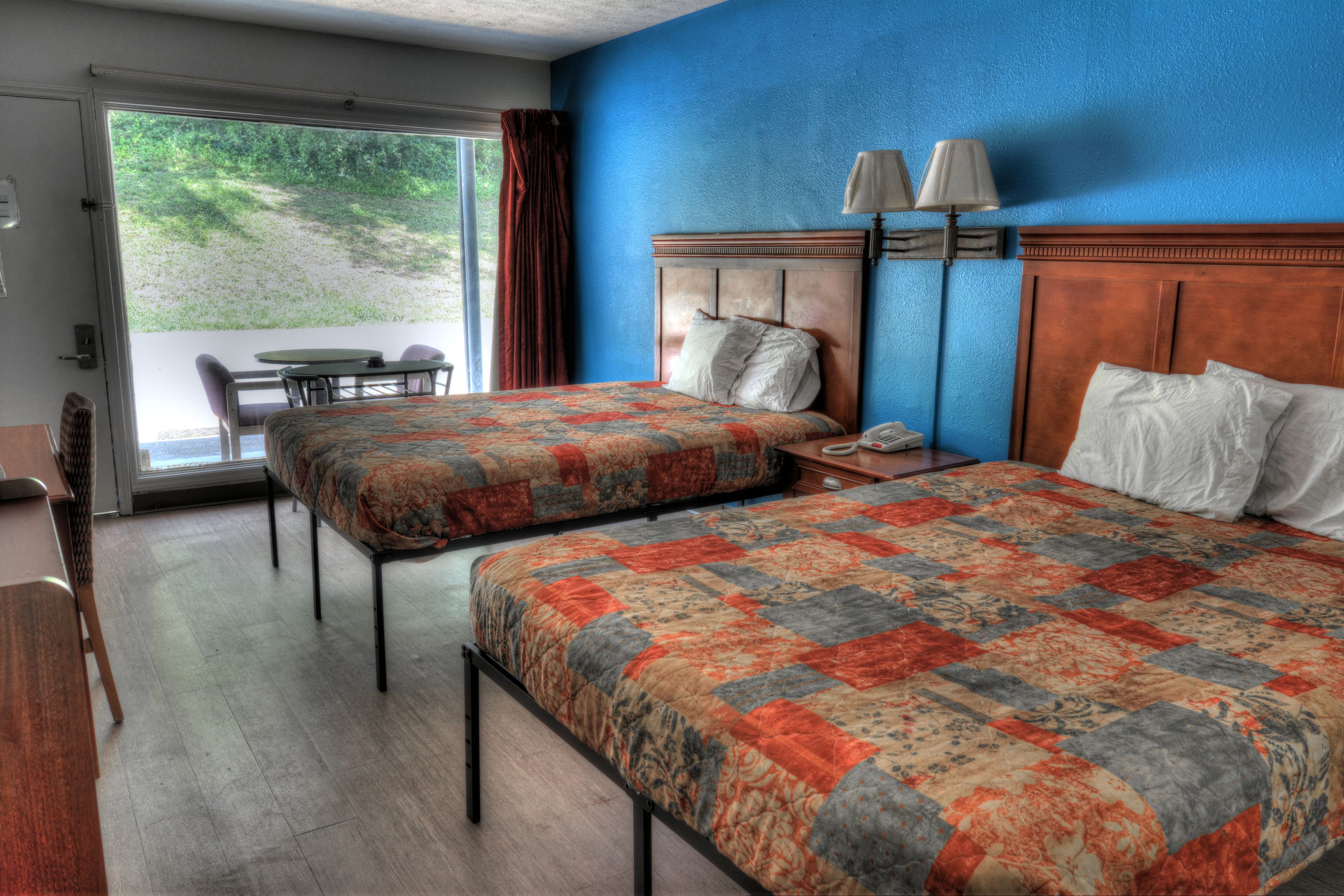 Een hotelkamer met twee bedden, een bureau, een stoel, een tafel en uitzicht op de omgeving.
