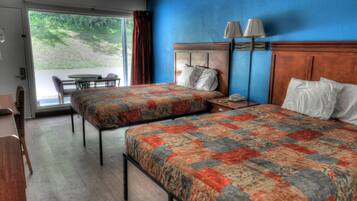 Een hotelkamer met twee bedden, een bureau, een stoel, een tafel en uitzicht op de omgeving.
