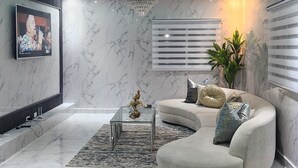 A modern living room with a marble floor, a curved sofa, a glass coffee table, and a TV mounted on the wall. - Charming 4-bedroom house with AC and WiFi in fabulous Punta Cana (Punta Cana)
