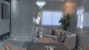 A modern dining area with a marble wall, a chandelier, and a sofa. - Charming 4-bedroom house with AC and WiFi in fabulous Punta Cana (Punta Cana)