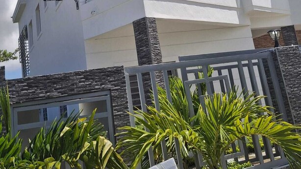 A modern two-story house with a balcony, stone accents, and a clear blue sky. - Charming 4-bedroom house with AC and WiFi in fabulous Punta Cana (Punta Cana)