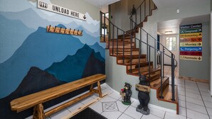 A staircase with wooden steps and metal railings, a wall mural with a mountain scene, and a bear figurine holding a 'Welcome' sign. - Sequoia's Dream: Mountain View, Spa, Heated Floors, Bar, Cinema! Near Yosemite! (Oakhurst)