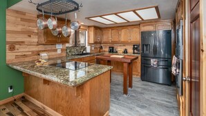 A kitchen with wooden cabinets, a granite countertop, a black refrigerator, and a skylight. - Sequoia's Dream: Mountain View, Spa, Heated Floors, Bar, Cinema! Near Yosemite! (Oakhurst)