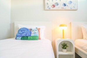 A neatly made bed with a colorful pillow arrangement and a bedside lamp.
