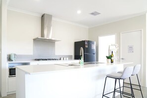 A modern kitchen with a central island, stainless steel appliances, and a bar area with stools.