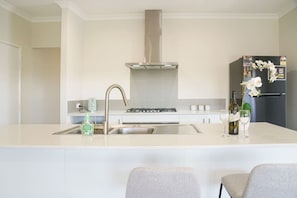A modern kitchen with a central island, stainless steel appliances, and a built-in oven. - StayAU 5BRM Idyllic Retreat for Families in Perth (Baldivis)