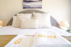 A neatly made bed with white linens and pillows, a headboard, and a painting on the wall. - StayAU 5BRM Idyllic Retreat for Families in Perth (Baldivis)