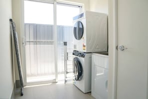 A laundry room with a washing machine, dryer, and a folding rack. - StayAU 5BRM Idyllic Retreat for Families in Perth (Baldivis)