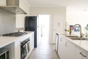 A modern kitchen with a gas stove, oven, and black refrigerator.