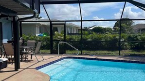 Uma piscina com cobertura de vidro, rodeada por espreguiçadeiras e um terraço coberto.