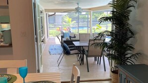 Uma sala de jantar com uma mesa posta para dois, um ventilador de teto e vista para o pátio externo.