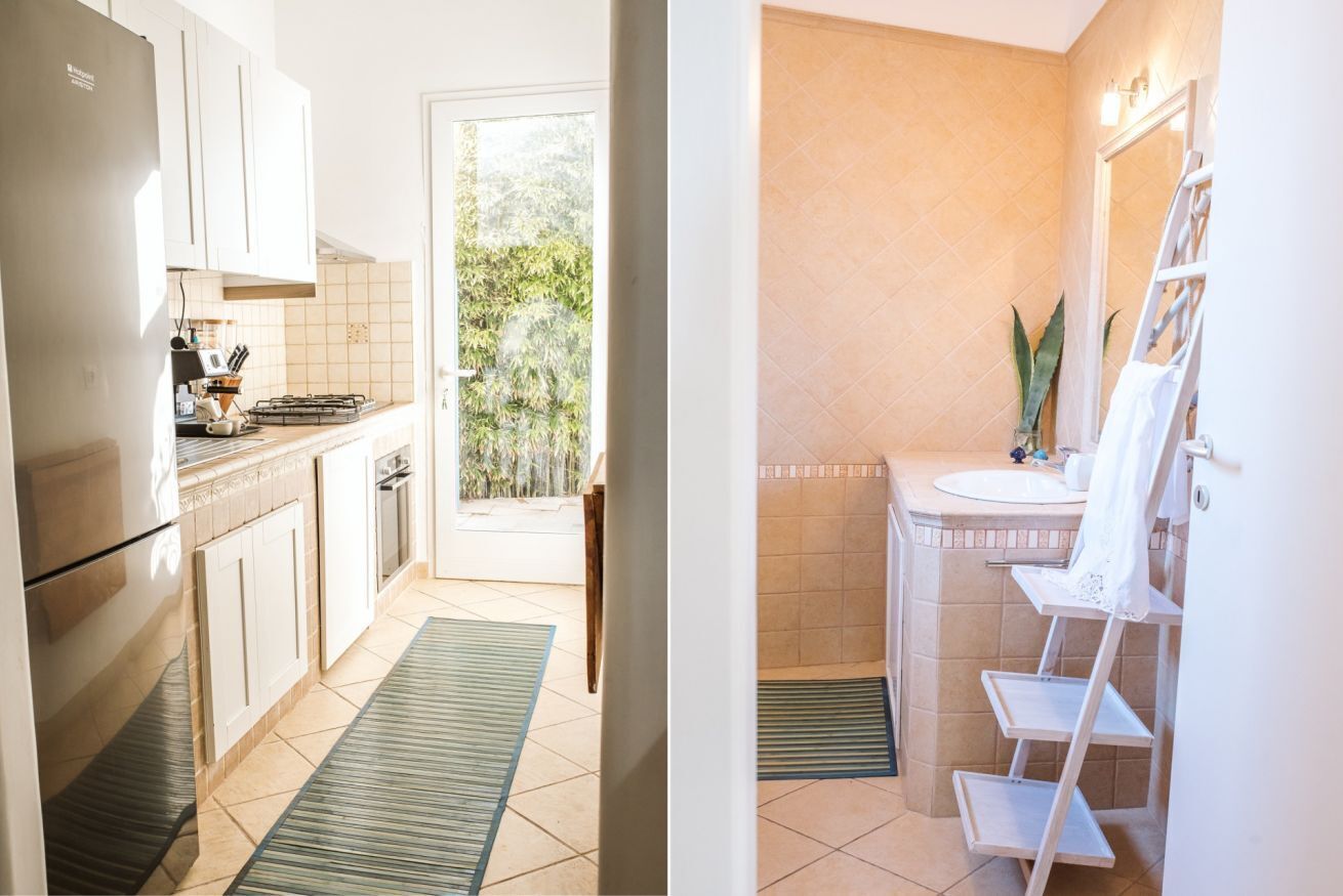 A compact kitchen with a refrigerator, stove, and cabinets, leading to a door with a view of greenery outside.