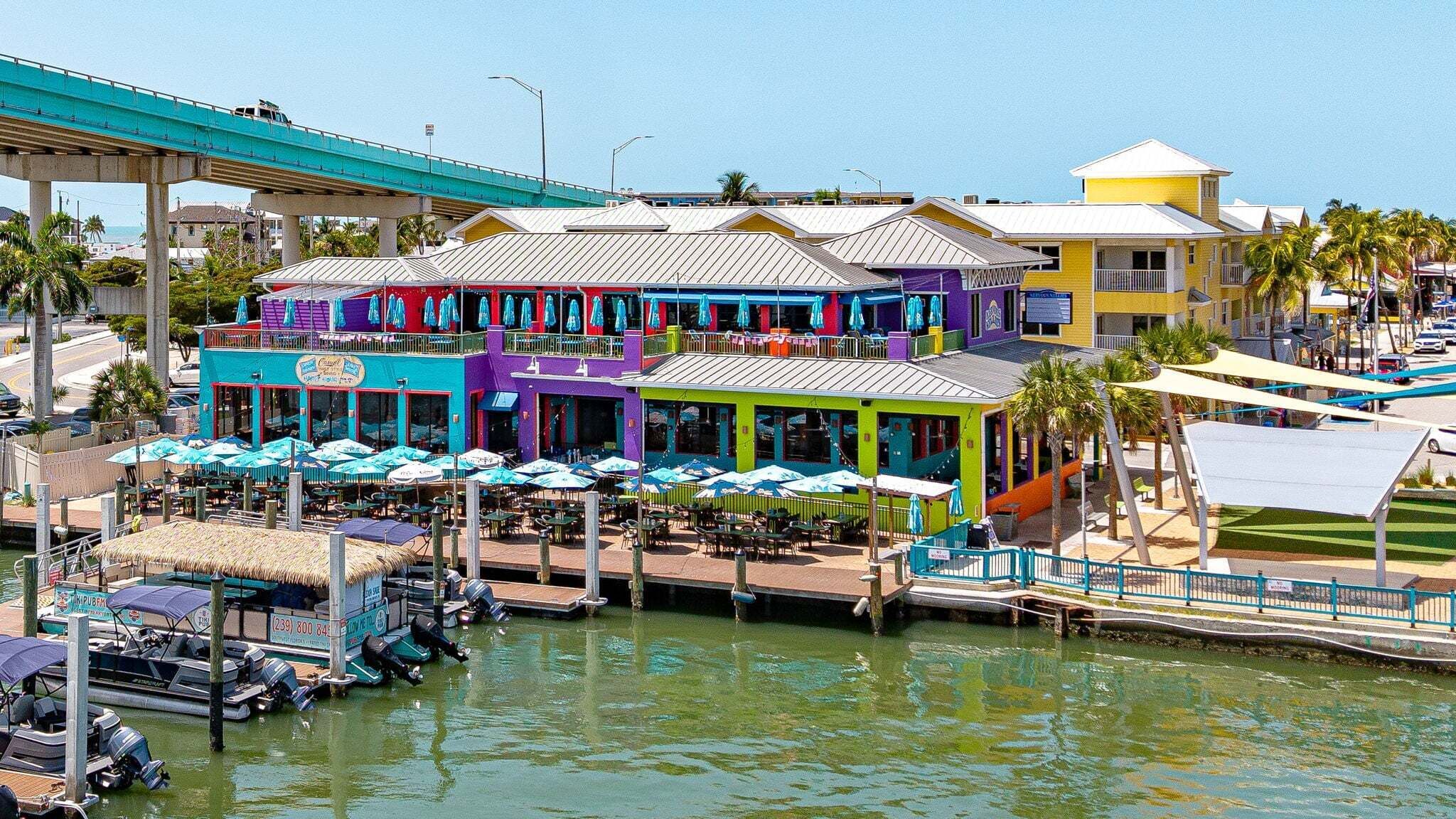 A waterfront restaurant with outdoor seating and a dock with boats.