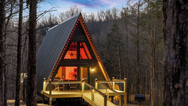 A wooden cabin with a sloped roof, a deck, and a mailbox. - LEDCabin, See the Stars, w/private Sauna, Hot Tub, on Creekfront (Omaha)