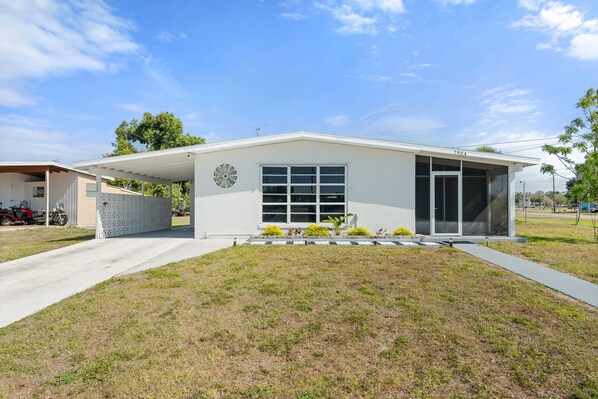 A modern single-story house with a covered porch, a large window, and a small garden area. - Nestled in North Port.  Updated 2 Bed / 1 Bath. (North Port)