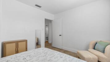 A bedroom with a bed, a wardrobe, a door, and a sofa.