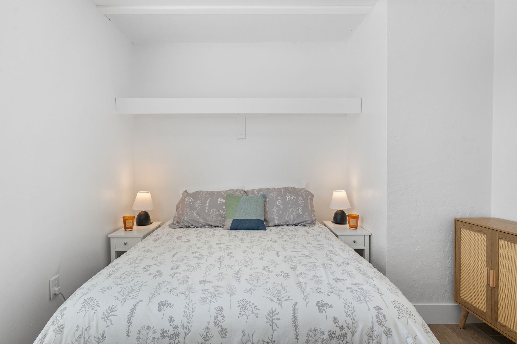 Ein Schlafzimmer mit einem Bett, zwei Nachttischen, einem Beistelltisch und einem Holzkasten.