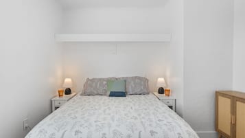 Ein Schlafzimmer mit einem Bett, zwei Nachttischen, einem Beistelltisch und einem Holzkasten.