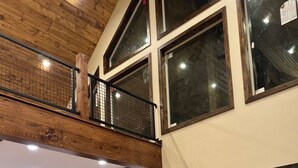 A spacious living room with a large sectional sofa, a wooden coffee table, and a balcony with a metal railing. - Buffalo Creek at Ponds Lodge Cabin 26 (Island Park)