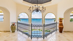 Un balcon spacieux offrant une vue dégagée sur la mer, un lustre décoratif et un grand vase.