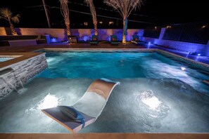 Una piscina con lettini prendisole e palme.