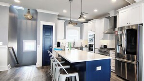 Una cocina moderna con una isla central, electrodomésticos de acero inoxidable y una pared de acento azul.