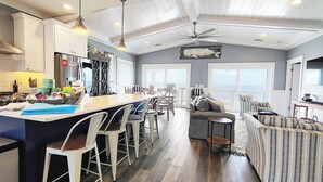 Una cocina amplia con una isla central, taburetes de bar y un comedor con vistas.