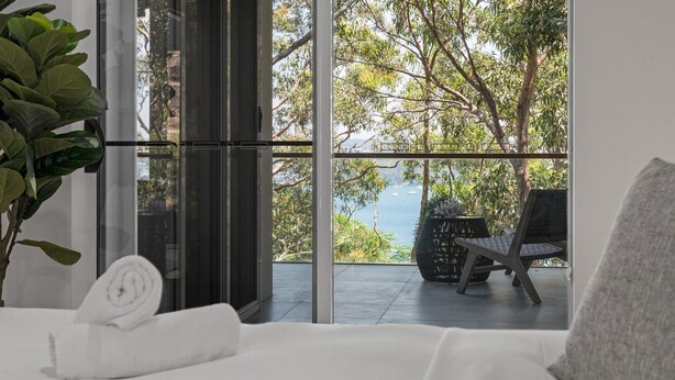 A modern room with a large glass door leading to a balcony with a view of the sea. - Sunlight Ridge House (Fishing Point)