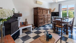 Una habitación con suelo a cuadros, un armario de madera, un televisor y una mesa de comedor con sillas.