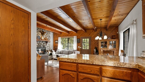 A spacious kitchen with wooden cabinets, granite countertops, and a stone fireplace.