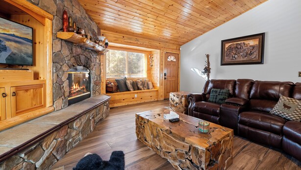 Un salon chaleureux avec une cheminée en pierre, un plafond en bois et un canapé en cuir.