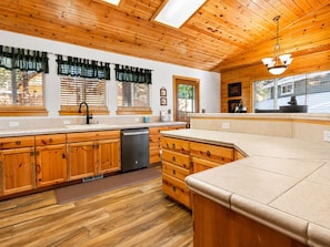 A kitchen with wooden cabinets, a dishwasher, and a large island.